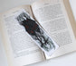 Bookmark with baba Yaga House and tree design on an open book